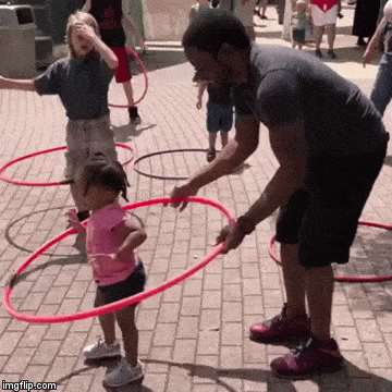 O pai ajuda a sua menina a rodar o hula hoop