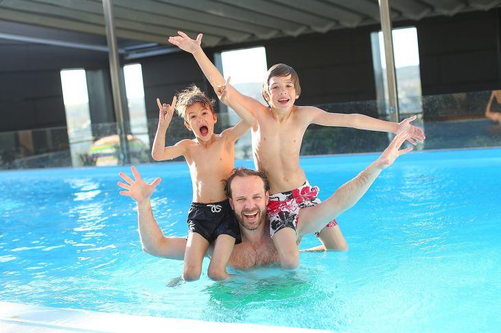Dad plays with sons in the pool