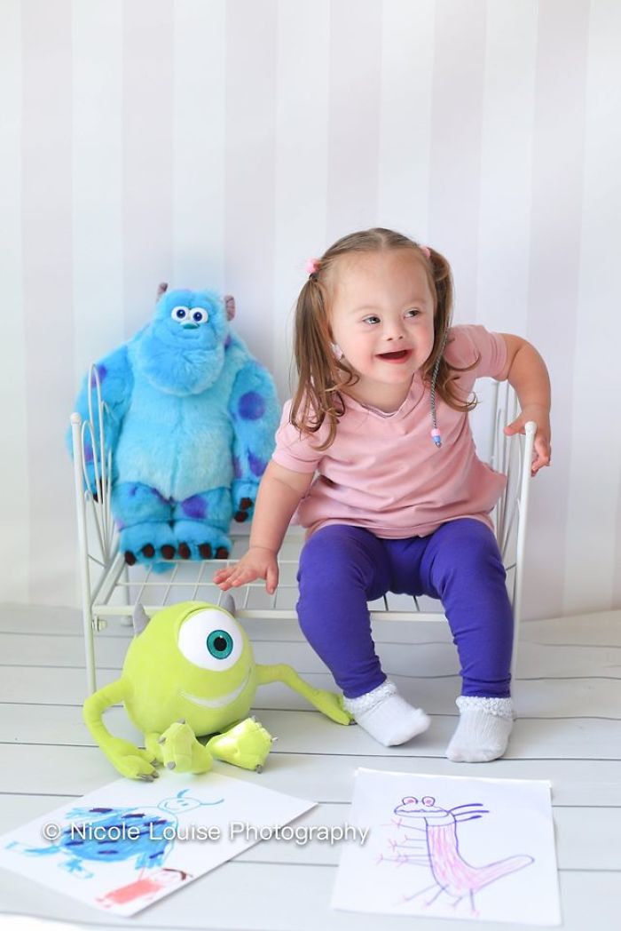 Garota com síndrome de Down senta-se com brinquedos