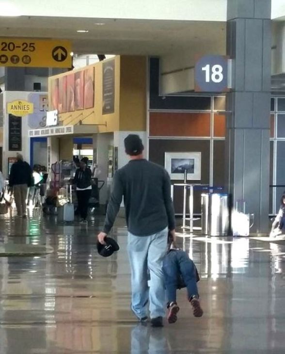 Papá lleva a un niño como una maleta
