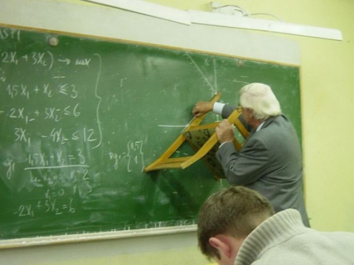 Teacher draws on the blackboard with a chair